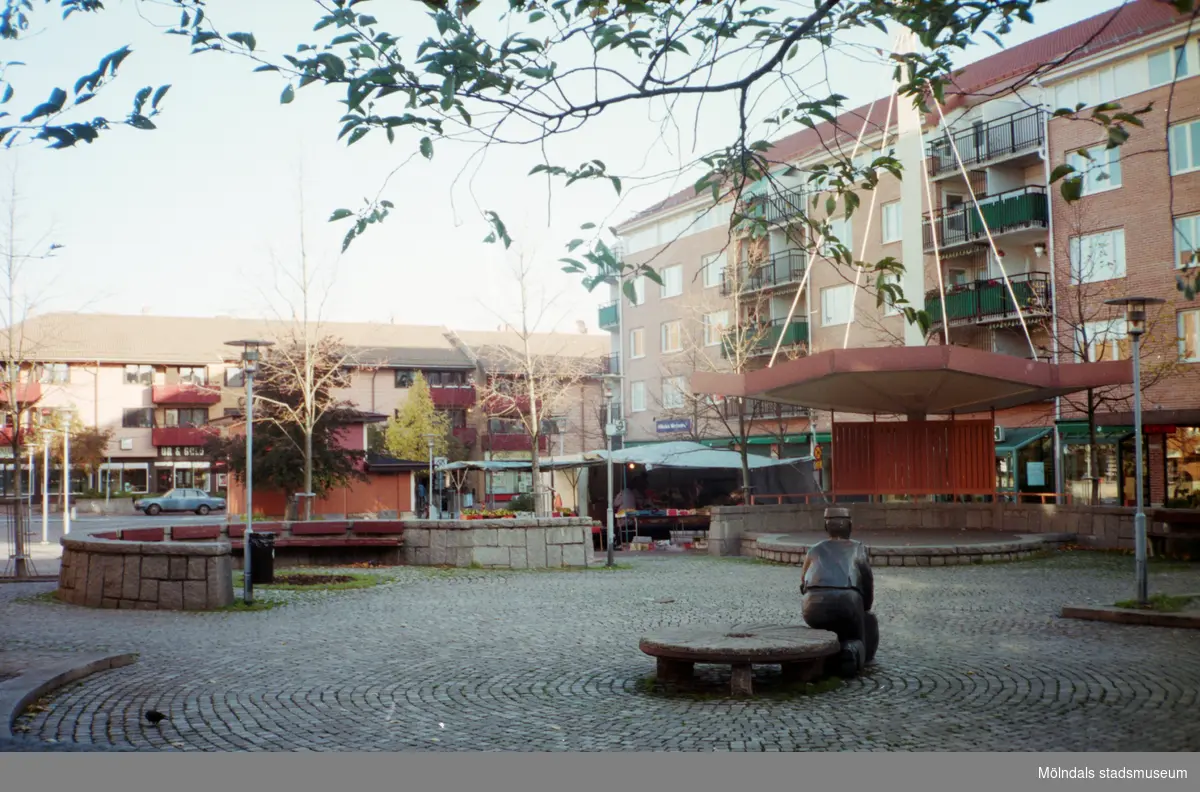 Skulpturen Albert och en scen på Mölndals torg. Mölndalsbro i dag - ett skolpedagogiskt dokumentationsprojekt på Mölndals museum under oktober 1996. 1996_1077-1078 är gjorda av högstadieelever från Kvarnbyskolan 9C, grupp 3. Se även 1996_0913-0940, gruppbilder på klasserna 1996_1382-1405 samt bilder från den färdiga utställningen 1996_1358-1381.