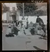 568 F. Stieg Trenter, Torremolinos. Människor samlade runt en springbrunn på ett torg. Stieg Trenter får sina skor putsade.