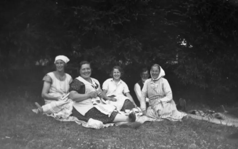 Gårdsfolk på Hallen 1:2. Till vänster sitter Valborg Magnusson och till höger Maria Magnusson med maken Fredrik i bakgrunden. I mitten ses sommargäster. 