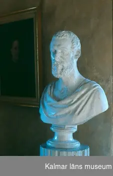 KLM 13081. Byst, med piedestal. Byst av gips, föreställande Carl XV. Piedestal av trä i form av vitmålad kannelerad kolonn. Signerad: HANSEN FEC 1850.