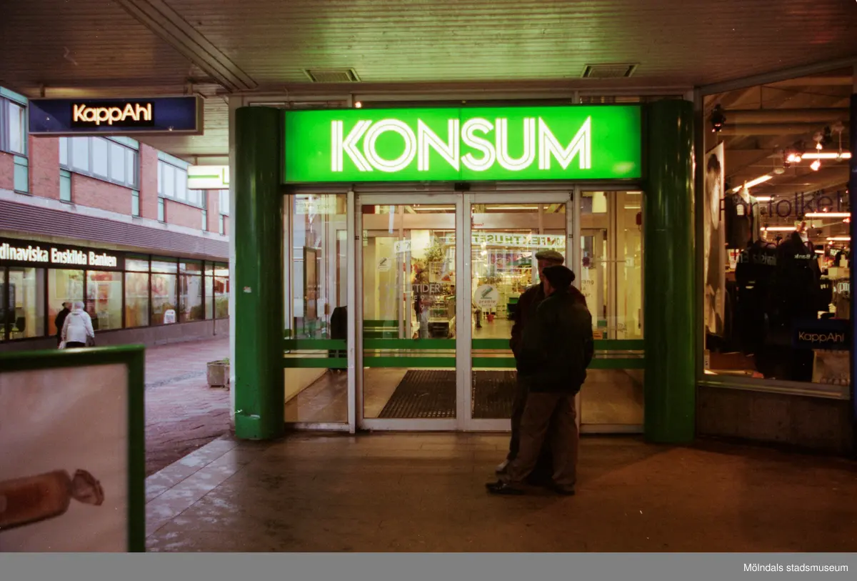 Huvudentré till Konsum på Brogatan. Mölndalsbro i dag - ett skolpedagogiskt dokumentationsprojekt på Mölndals museum under oktober 1996. 1996_1135-1152 är gjorda av högstadieelever från Kvarnbyskolan 9D, grupp 1. Se även 1996_0913-0940, gruppbilder på klasserna 1996_1382-1405 samt bilder från den färdiga utställningen 1996_1358-1381.