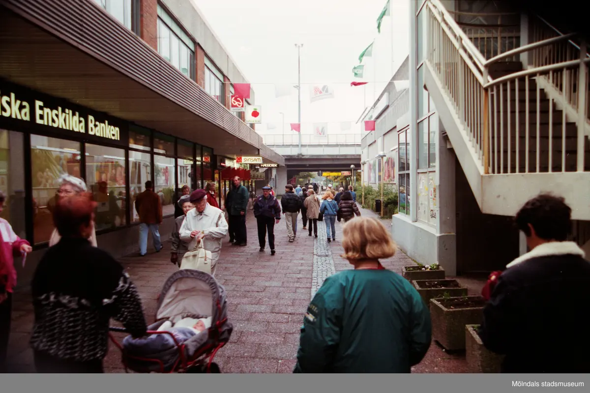 Nygatan söderut där bron skymtar i fonden. Trappan till P-däcket ses till höger. Mölndalsbro i dag - ett skolpedagogiskt dokumentationsprojekt på Mölndals museum under oktober 1996. 1996_1153-1171 är gjorda av högstadieelever från Kvarnbyskolan 9D, grupp 2. Se även 1996_0913-0940.