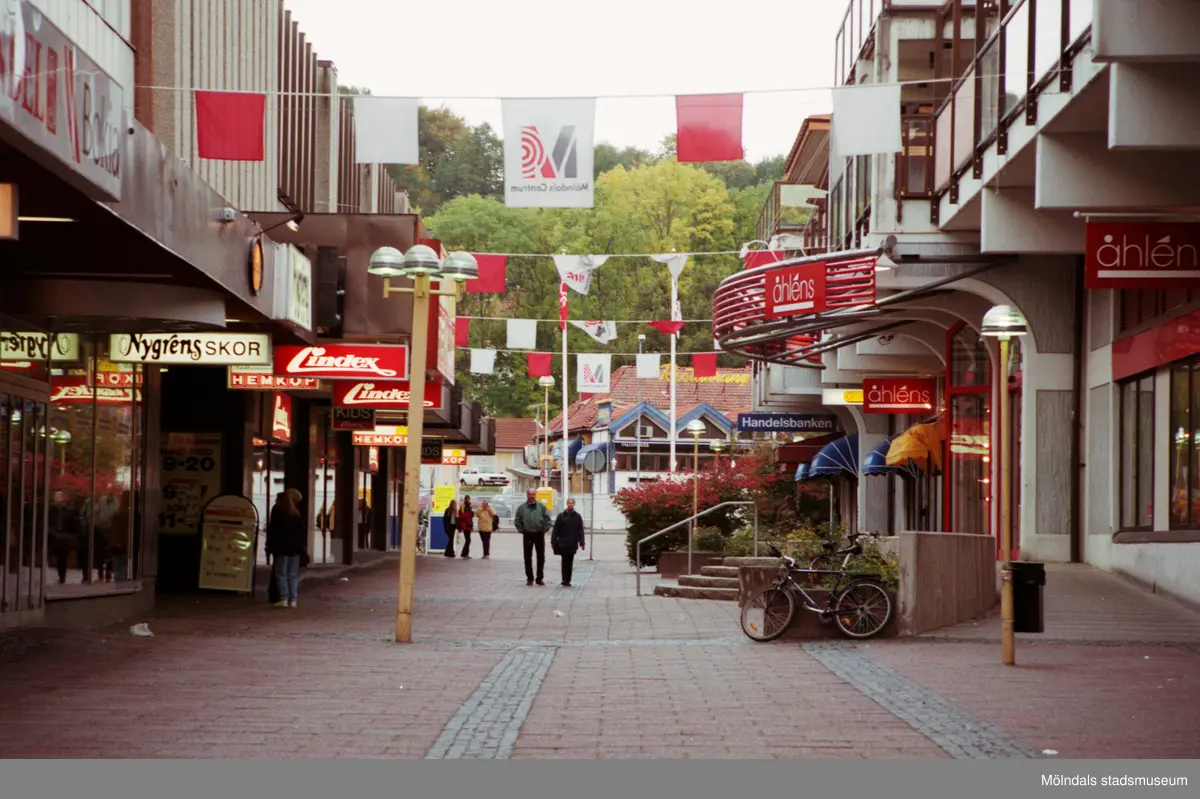 Brogatans västra del. Sahlins terrass ses i fonden på andra sidan Storgatan. Mölndalsbro i dag - ett skolpedagogiskt dokumentationsprojekt på Mölndals museum under oktober 1996. 1996_1246-1263 är gjorda av högstadieelever från Åbyskolan 8A, grupp 1. Se även 1996_0913-0940, gruppbilder på klasserna 1996_1382-1405 och bilder från den färdiga utställningen 1996_1358-1381.