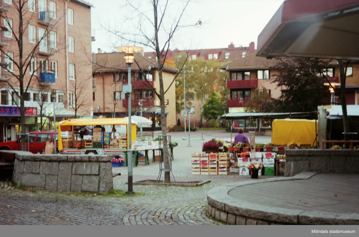 Torghandel på Mölndals torg. I bakgrunden ses Bergmansgatan. Mölndalsbro i dag - ett skolpedagogiskt dokumentationsprojekt på Mölndals museum under oktober 1996. 1996_1320-1337 är gjorda av högstadieelever från Åbyskolan 8A, grupp 5. Se även 1996_0913-0940, gruppbilder på klasserna 1996_1382-1405 och bilder från den färdiga utställningen 1996_1358-1381.