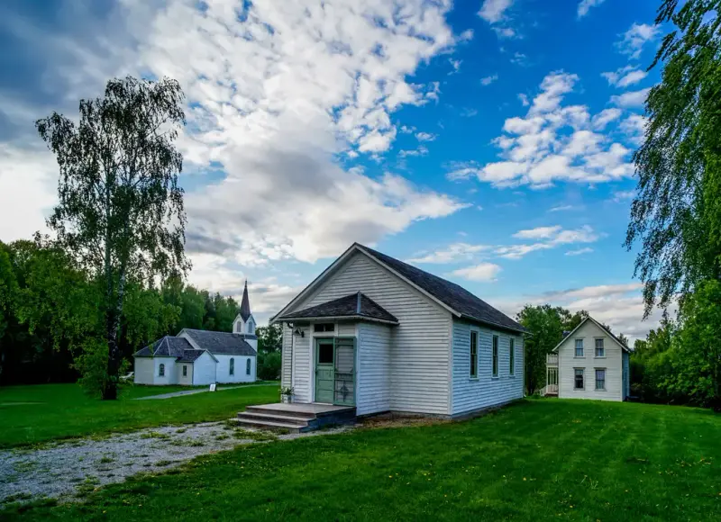 foto av friluftsmuseet på Norsk Utvandrermuseum. I bilde sees skolebygningen og kirken