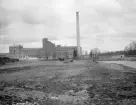 Linköpings sockerfabrik 1906, invigd under föregående år. Anläggningen är väl dokumenterad i bild, vilket inte kan sägas om den blygsamma vattenspegeln till höger. Den så kallade Rudsjön hade bildats som en följd av höjt vattenstånd i Stångån efter att dammanläggningen i Nykvarn byggts 1867. Den lilla sjön blev till glädje för skridskoåkande barn men även ett gissel för stadens styre som ansåg att området behövdes för andra och mer trängande ändamål. Tidigt tycks den bitvis börjat fyllas igen, om än inte kontrollerat. På förekommen anledning lät Drätselkammaren vid upprepade tillfällen erinra att där endast fick avstjälpas sten, grus, jord och lera. I ett januarinummer 1896 lät man genom Östgöta Correspondenten meddela att 