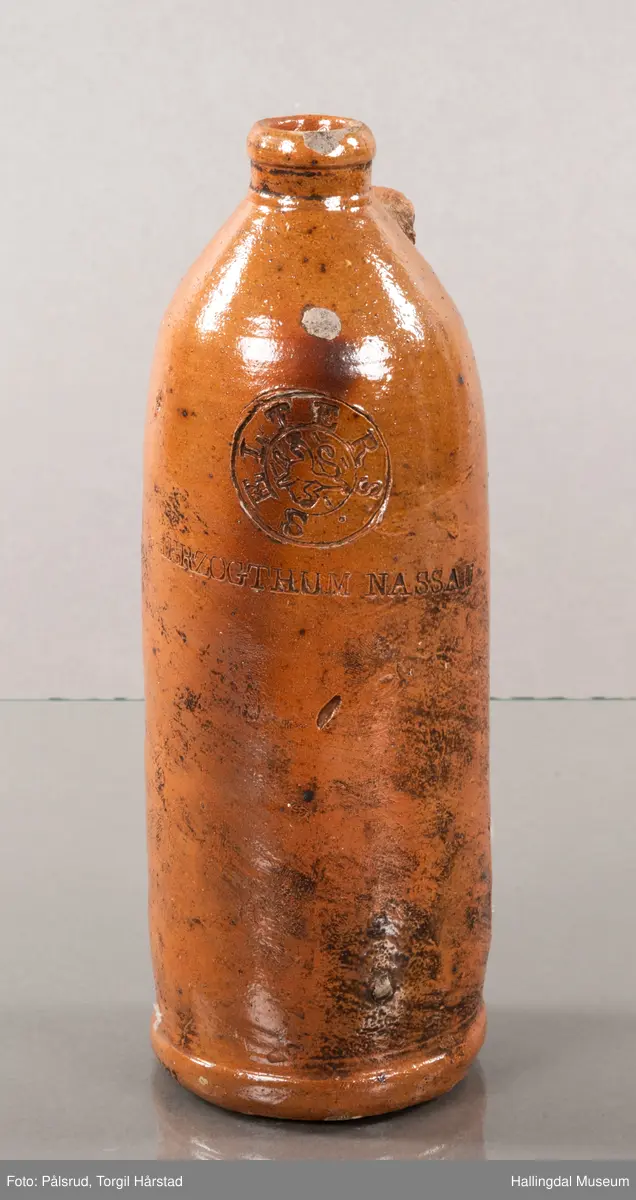 Keramikkflaske med ødelagt hank. Rustbrun, glassert.