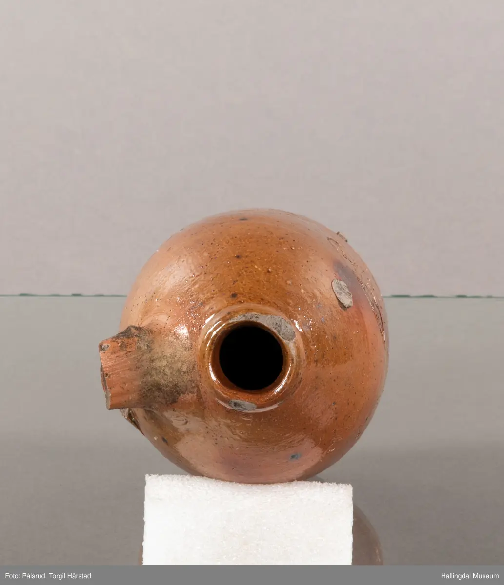 Keramikkflaske med ødelagt hank. Rustbrun, glassert.