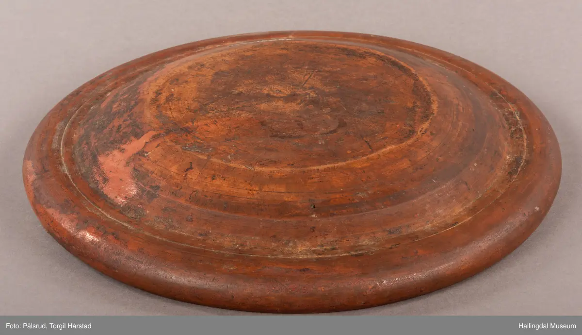 Brunt keramikkfat med dekor i grønt og hvitt. Glassert. Grønn tulipan på midten med tykk hvit bord rundt. Bølget grønn bord langs kanten med hvit tynn bord ytterst.