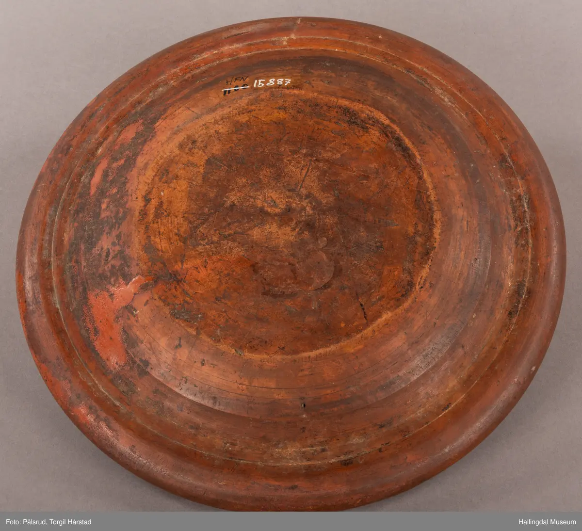 Brunt keramikkfat med dekor i grønt og hvitt. Glassert. Grønn tulipan på midten med tykk hvit bord rundt. Bølget grønn bord langs kanten med hvit tynn bord ytterst.