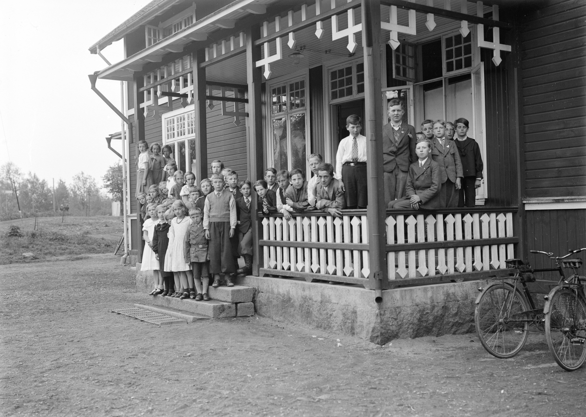 Det blev fullt på verandan när kyrkskolans elever samlades för fotografering. Bland barnen har Emmy Ax identifierats. Vi ser henne till höger om stolpen invid trappan. Året var 1935.