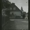 På en gavelfasad på Skolgränden hänger hästskor. I bakgrunden Sankt Clemens kyrka, Laholm.