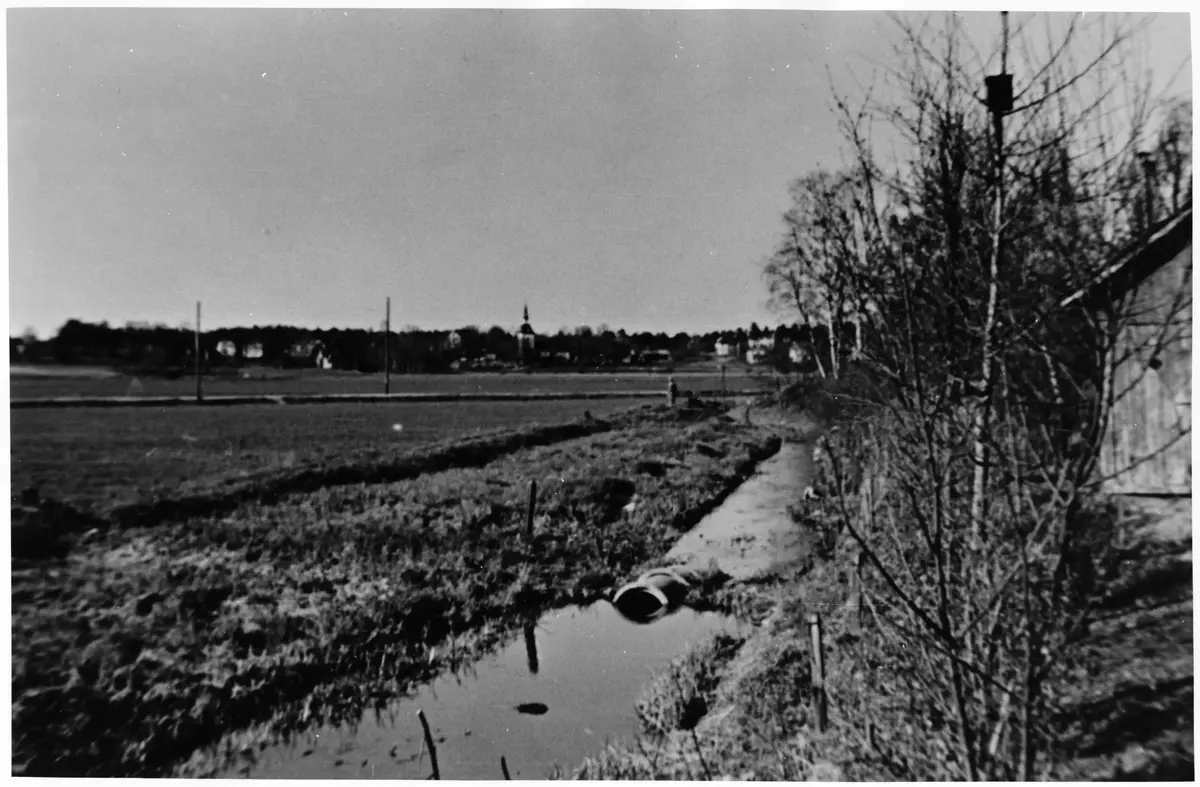 Sjöängen år 1925.
 ; BHF Studiecirkel vt 2016:
Bilden tagen ungefär från Helgarögränd mot kyrkan. Rågfeldts uthus t.h. i förgrund. Tidigare cykelväg ovanpå dräneringskulverten syns horisontellt i bild.