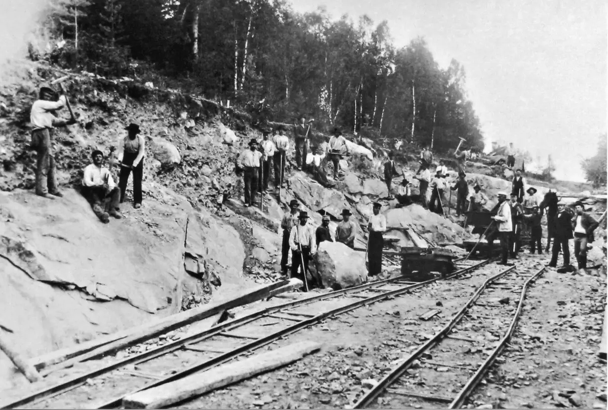 Bygget av Nynäsbanan. Banbygget pågick 1898-1901. Huvuddelen av arbetet utfördes med handkraft. Som mest sysselsattes över 300 man med bygget. Ett av de få hjälpmedel man hade var s.k. decuavilletrallor för transport av schaktmassor. Samma typ av trallor används
idag Nynäshamns tågmuseets kolgård bakom lokstallet