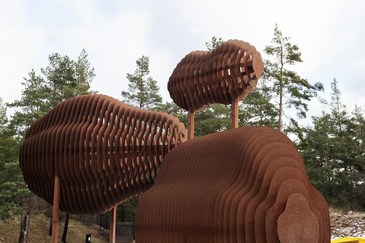 Om konstverket

Skyttlar är ett konstverk tillverkat i corténstål. Det står placerat i anslutning till entrén till Storkällans kapell och kyrkogård i Nacka.


Platsen

Storkällan är ett kapell vilket innebär att man inte behöver vara kristen för att kunna använda platsen. Man har med den konstnärliga gestaltningen bland annat velat skapa en värdig entré till begravningsplatsen och framhöll i uppdragsbeskrivningen att konstverket gärna fick utgöra en blinkning till den arkitektur som Storkällans kapell och begravningsplats består av.
Skyttlar knyter an till den redan på förhand tydligt definierade entrén. Materialet corténstål åldras vackert och harmoniserar med platsens övriga material och omgivningar. Detta är ett par aspekter som beställaren Nacka kommun och delfinansiären Nacka församling efterfrågade då man gav konstnären Hanna Stahle i uppdrag att konstnärligt gestalta Storkällan/Ältadalen. Planen och förhoppningen är att man skall uppleva vägen fram till entrén som en signal om vad som komma skall.

Om konstnären

Då Hanna Stahle besöker platsen tänker hon på de flöden av människor som passerar här; Bussen som rundar planen, bilar som kör vidare in till begravningsplatsen, gående och cyklister som går i alla riktningar mellan busshållplatsen, arbetsplatserna, hemmen, friluftsområdena och begravningsplatsen.