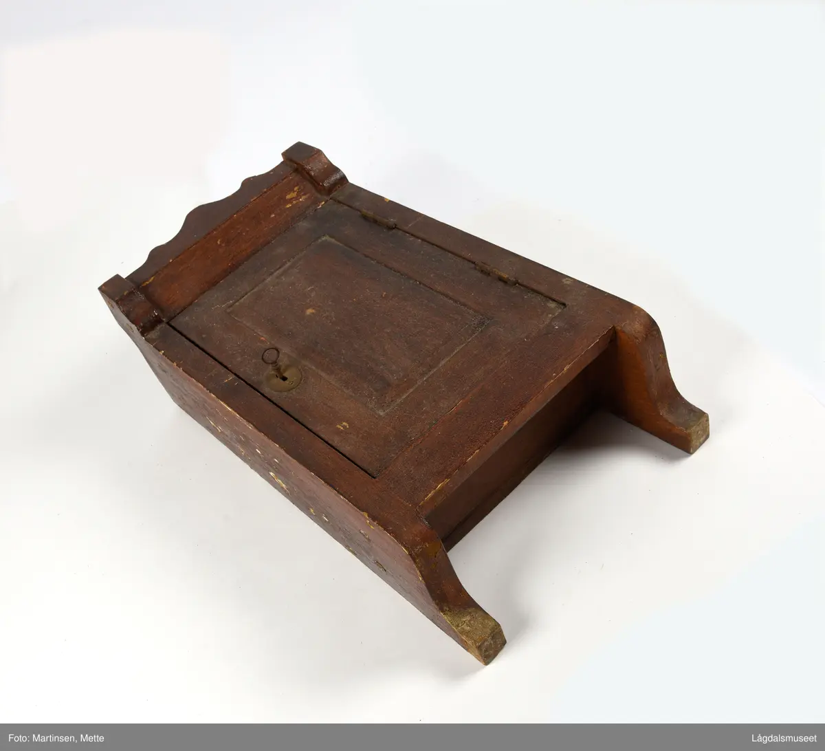 Hengeskap med hengslet dør. Dør med markert speil. Lås med nøkkel. Innvendig er det tre hyller. Beslag for oppheng.