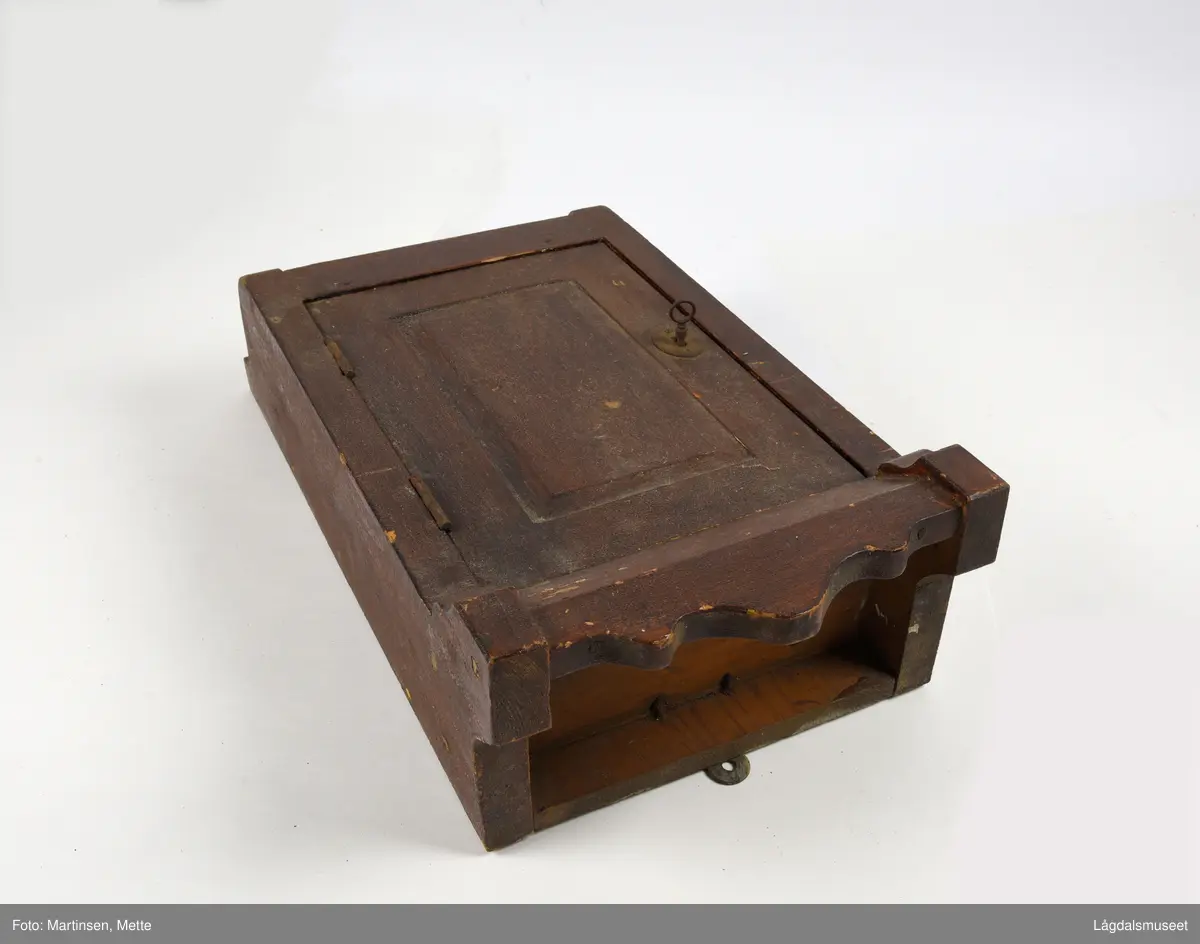 Hengeskap med hengslet dør. Dør med markert speil. Lås med nøkkel. Innvendig er det tre hyller. Beslag for oppheng.