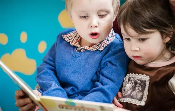 To småborn som ser i ei bok