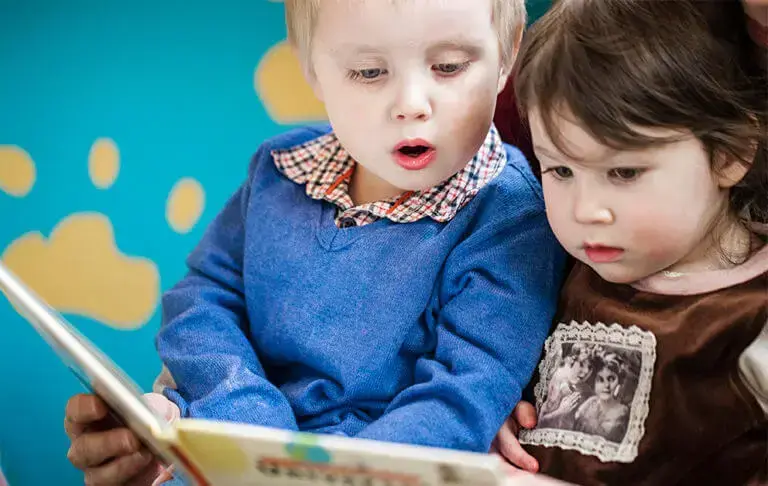 To småborn som ser i ei bok