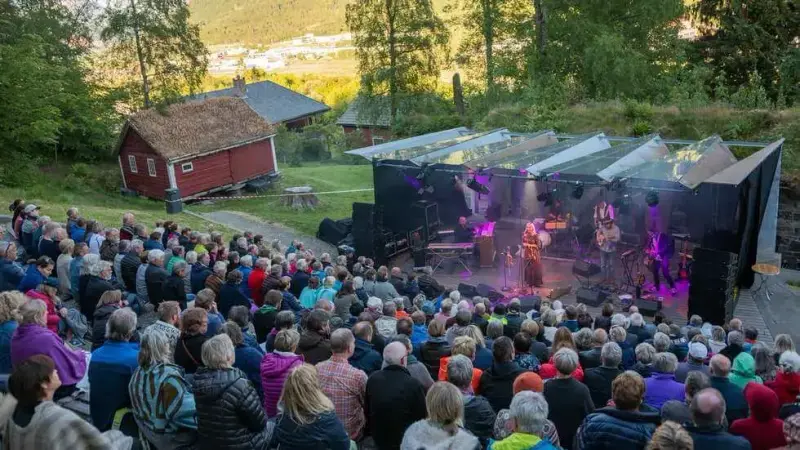 Oversiktsbilde av fullsett uteamfi og scene med artistar