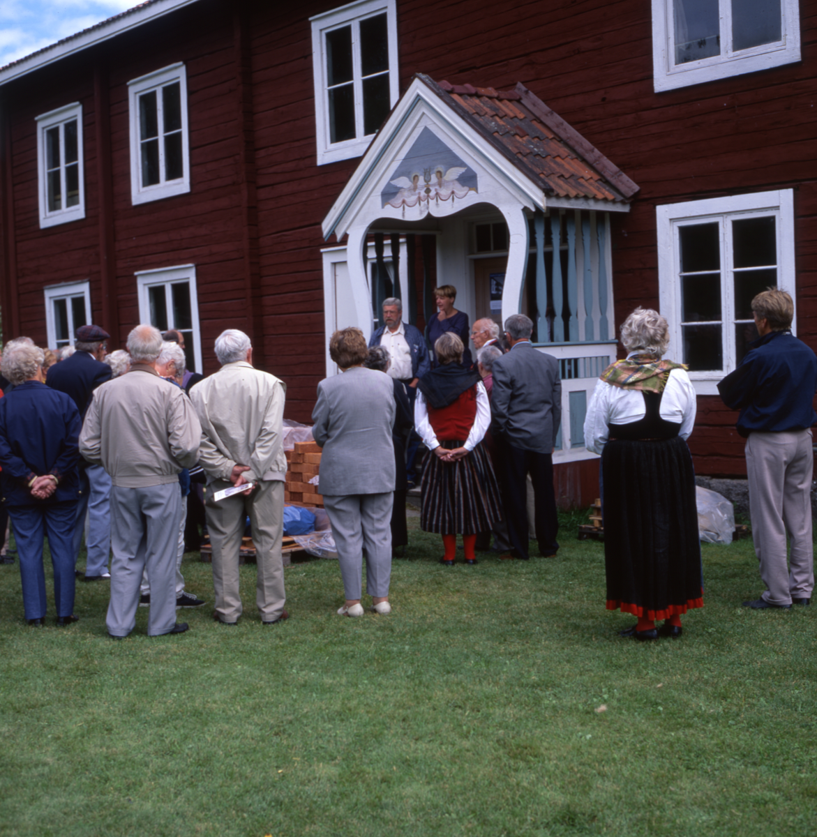 En grupp människor har samlats utanför ett hus.