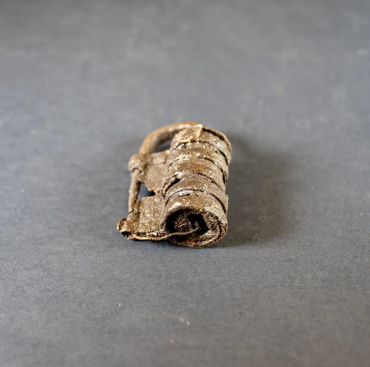 Låshuset cylindriskt med utanpåliggande ringar. Hängbult och regelskiva intakta, nyckelhål i gaveln. Låset har varit i två delar men är lagat i senare tid (vid konserveringen?) med en (koppar)tråd
Av järn, 3 tum långt, avbrutet på mitten