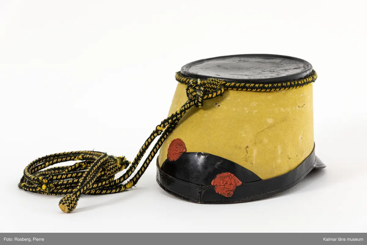 KLM 15169:2. Hakrem. Till Husarmössa. Modell 1884. Smålands Husarregemente, Livskvadron. Rem av brunt läder. Knäpps med spänne av gulmetall och hål, elva st. En hälla av läder vid metallspännet samt en lika hälla som är flyttbar över remmen.
Hakremmen förvaras i mössa KLM 15169:1.