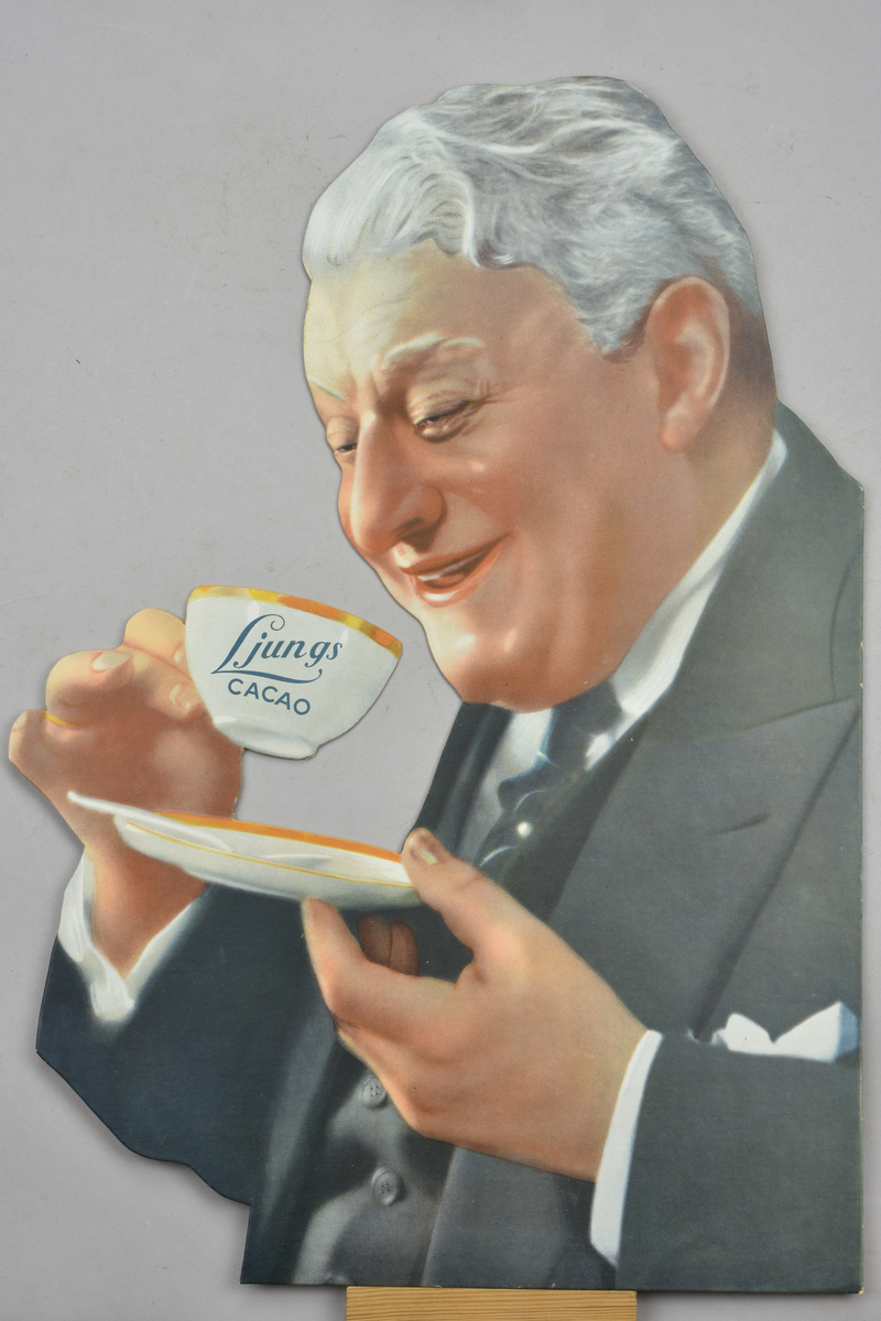 Reklamskylt med motiv av en äldre man med en kopp i handen. Utstansad kartong. Text: "Ljungs Cacao".