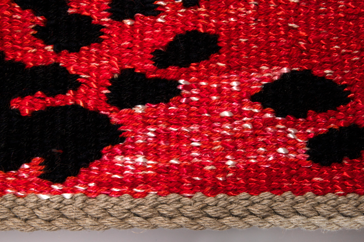 Rektangulær billedvev i gobelengteknikk, lingarn i renningen og ull og syntetgarn i innslaget. Abstrakt motiv i sterke, lysende farger. Åtte brede strenger i ulike farger på lys bunn (hver farge er satt sammen av sjatteringer i fargens tone) er flettet diagonalt i hverandre. Over dette et mønster i svart, som er inspirert av gamle stofftrykkblokker. Renningstrådene er flettet til et horisontalt bånd i øvre og nedre kant.