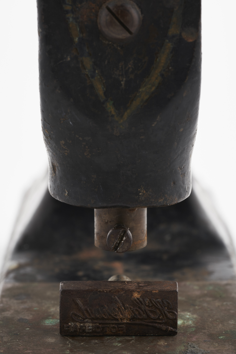 Signaturstempel i jern. Håndtaket presses ned og merker papir eller fotografi med fotografens stempel. Følgende logo presses inn:  H. Haslerud. FOTOGRAF

Diverse fotoutstyr og andre gjenstander som har tilhørt Synnøve Brændshøi sitt fotoatelier. De fleste er nok fra 40- og 50-tallet. 