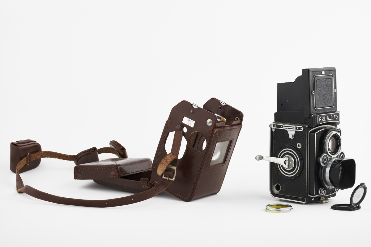 Kamera med tilhørende futteral/veske i brunt lær med fløyel på innsiden. Kameraet er et twin lens av merke Rolleiflex, trolig av modellen 2.8, produsert fra 1949 til 1956. Det har en Heidosmat 1:2,8/75 linse. Kameraetuiet har små vesker med diverse tilbehør. Har tilhørende bruksanvisning på tysk, med manglende forside.

Samlingen består av diverse fotoutstyr og andre gjenstander som har tilhørt Synnøve Brændshøi sitt fotoatelier. De fleste er nok fra 1940- og 50-tallet.