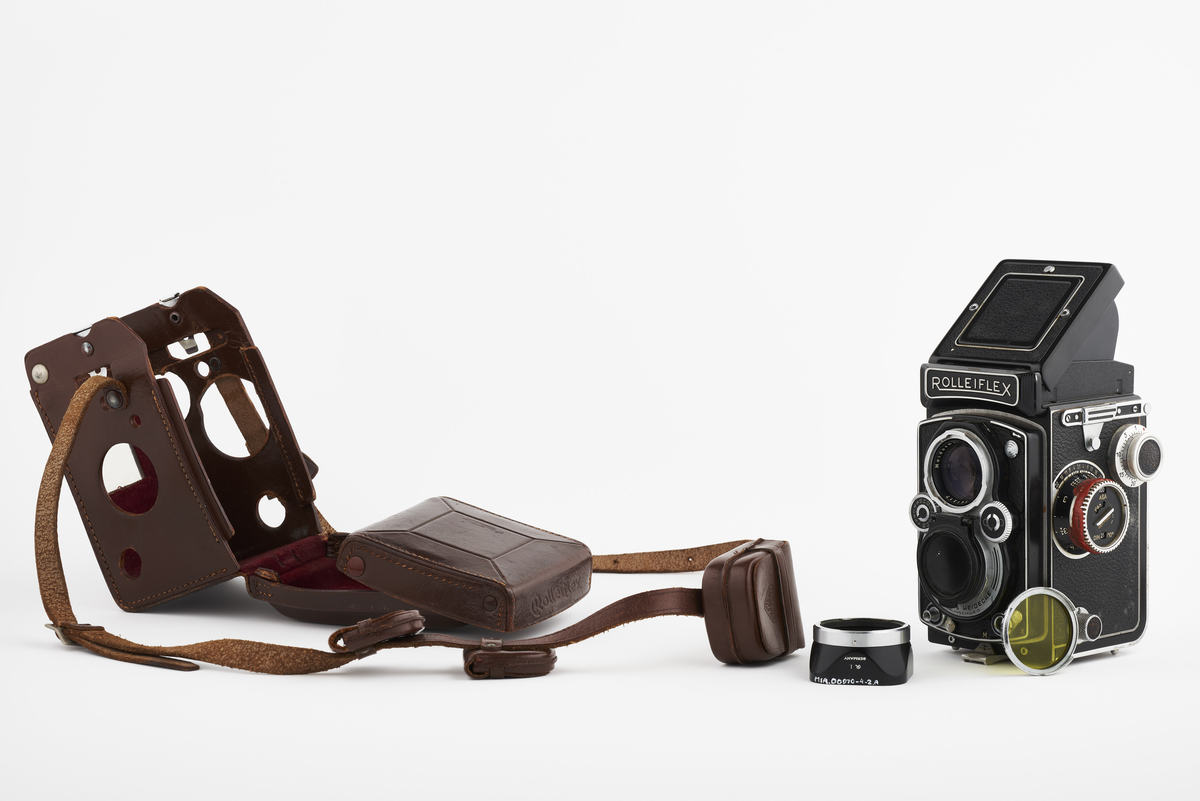 Kamera med tilhørende futteral/veske i brunt lær med fløyel på innsiden. Kameraet er et twin lens av merke Rolleiflex, trolig av modellen 2.8, produsert fra 1949 til 1956. Det har en Heidosmat 1:2,8/75 linse. Kameraetuiet har små vesker med diverse tilbehør. Har tilhørende bruksanvisning på tysk, med manglende forside.

Samlingen består av diverse fotoutstyr og andre gjenstander som har tilhørt Synnøve Brændshøi sitt fotoatelier. De fleste er nok fra 1940- og 50-tallet.