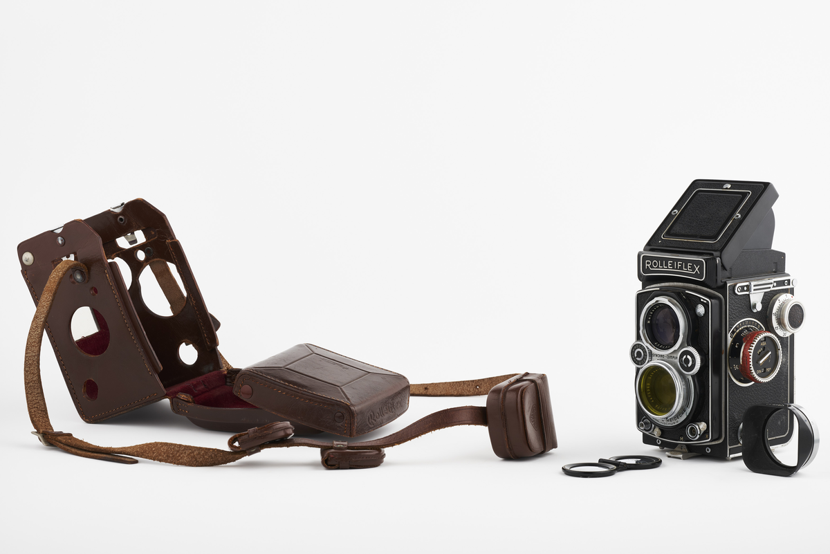 Kamera med tilhørende futteral/veske i brunt lær med fløyel på innsiden. Kameraet er et twin lens av merke Rolleiflex, trolig av modellen 2.8, produsert fra 1949 til 1956. Det har en Heidosmat 1:2,8/75 linse. Kameraetuiet har små vesker med diverse tilbehør. Har tilhørende bruksanvisning på tysk, med manglende forside.

Samlingen består av diverse fotoutstyr og andre gjenstander som har tilhørt Synnøve Brændshøi sitt fotoatelier. De fleste er nok fra 1940- og 50-tallet.