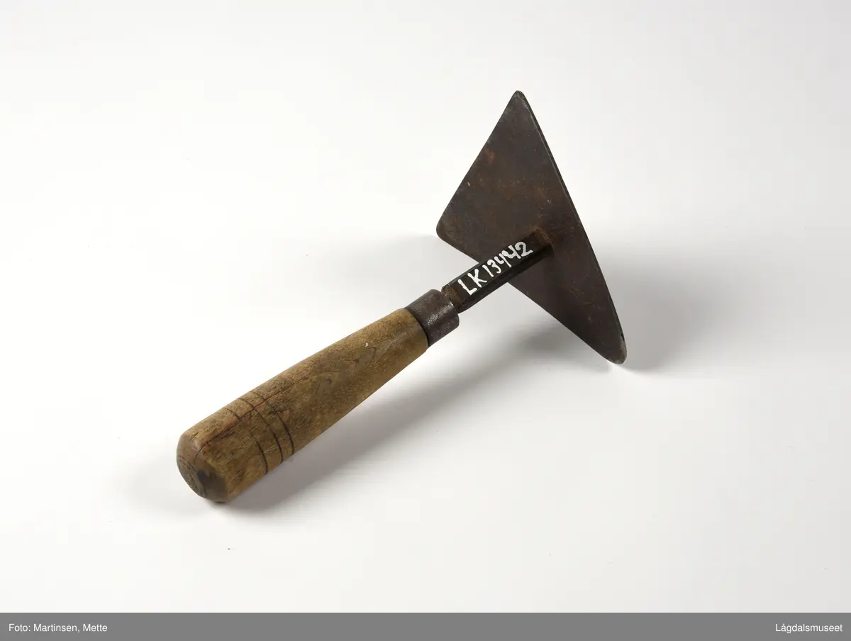 Skåldeskraper brukt til å skrape vekk busta fra grisen etter skålding med varmt vann. Trekantet metallplate festet til et treskaft.