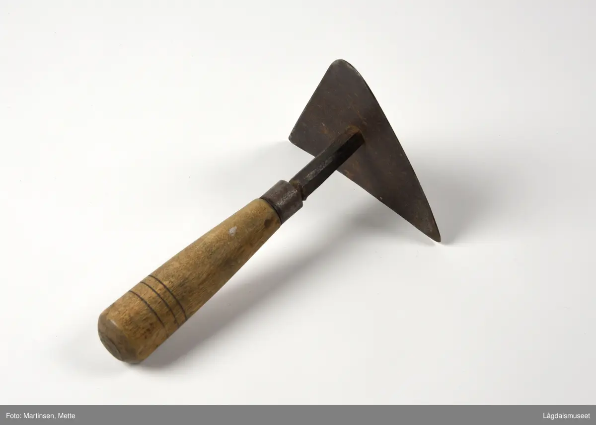 Skåldeskraper brukt til å skrape vekk busta fra grisen etter skålding med varmt vann. Trekantet metallplate festet til et treskaft.