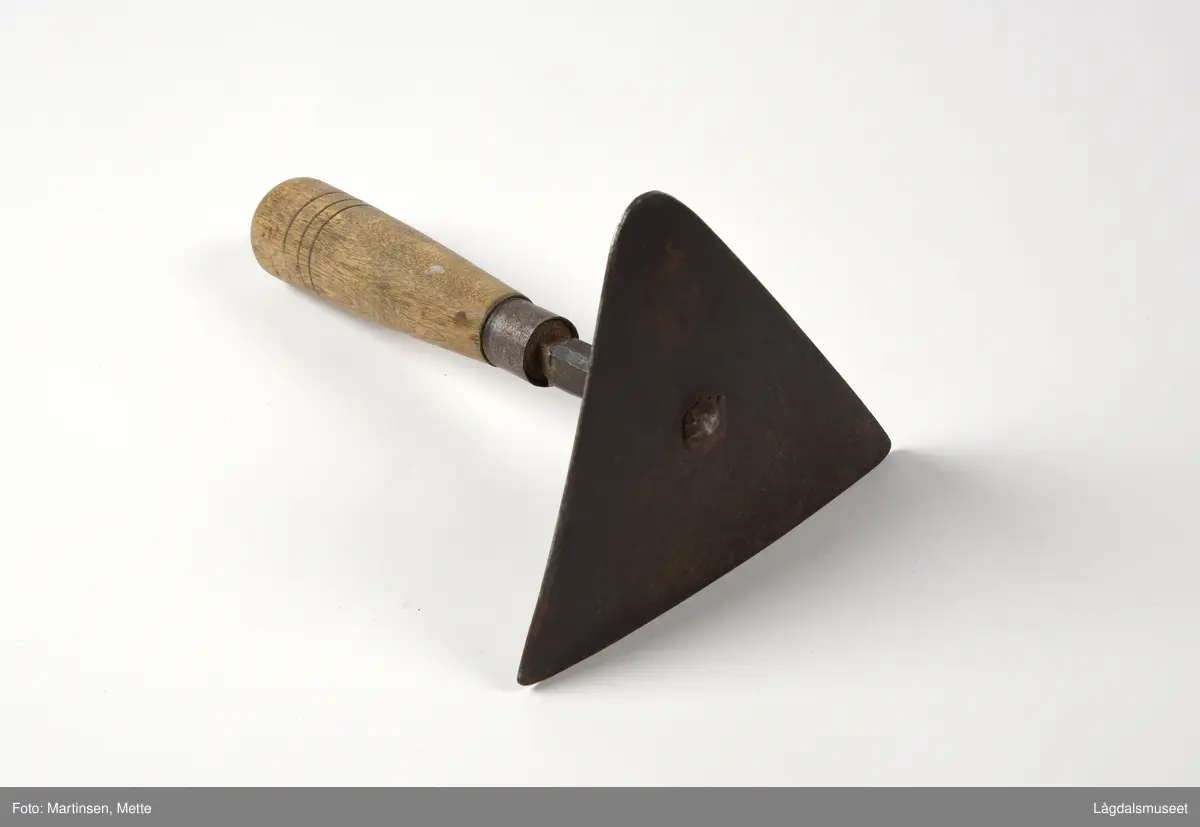 Skåldeskraper brukt til å skrape vekk busta fra grisen etter skålding med varmt vann. Trekantet metallplate festet til et treskaft.