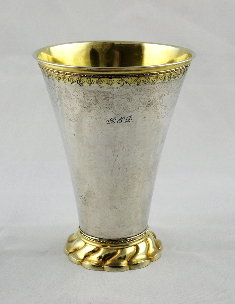 Konisk bägare av silver med förgyllning och gravyr.
