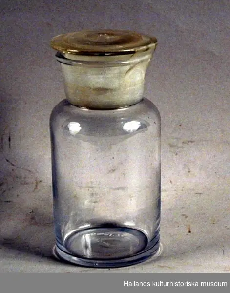 Burk, så kallad apoteksglas. a) Burk. Cylindrisk. b) Glaspropp.