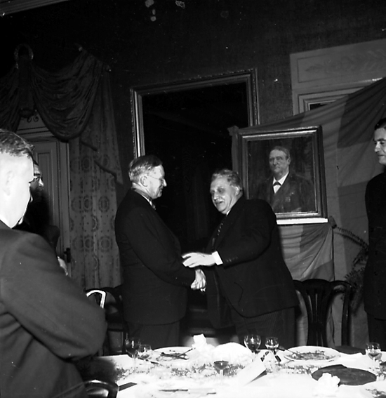 Män i någon form av ceremoni. Förmodligen vid jubileum. Mannen till höger är troligtvis Abraham Unger, landshövding i Värmlands län 1921-1936.
Fotografens ant: AB. C.J. Wennbergs Mek. 
Som ung smedlärling flyttade Carl Johan Wennberg år 1864 till Karlstad. Några år senare startade han en mindre verkstad för reparationer av redskap, vagnar och båtar och därmed lades grunden till företaget, AB C.J Wennbergs Mekaniska Verkstad. På 1890-talet uppfördes ett eget gjuteri i stadsdelen Viken, beläget intill Mariebergsviken.
Källa: Nyblom-Svanqvist, Näringsliv i Värmland, 1945