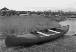 Byggnader med vattendrag, samt kanot i förgrunden.
Fotografe