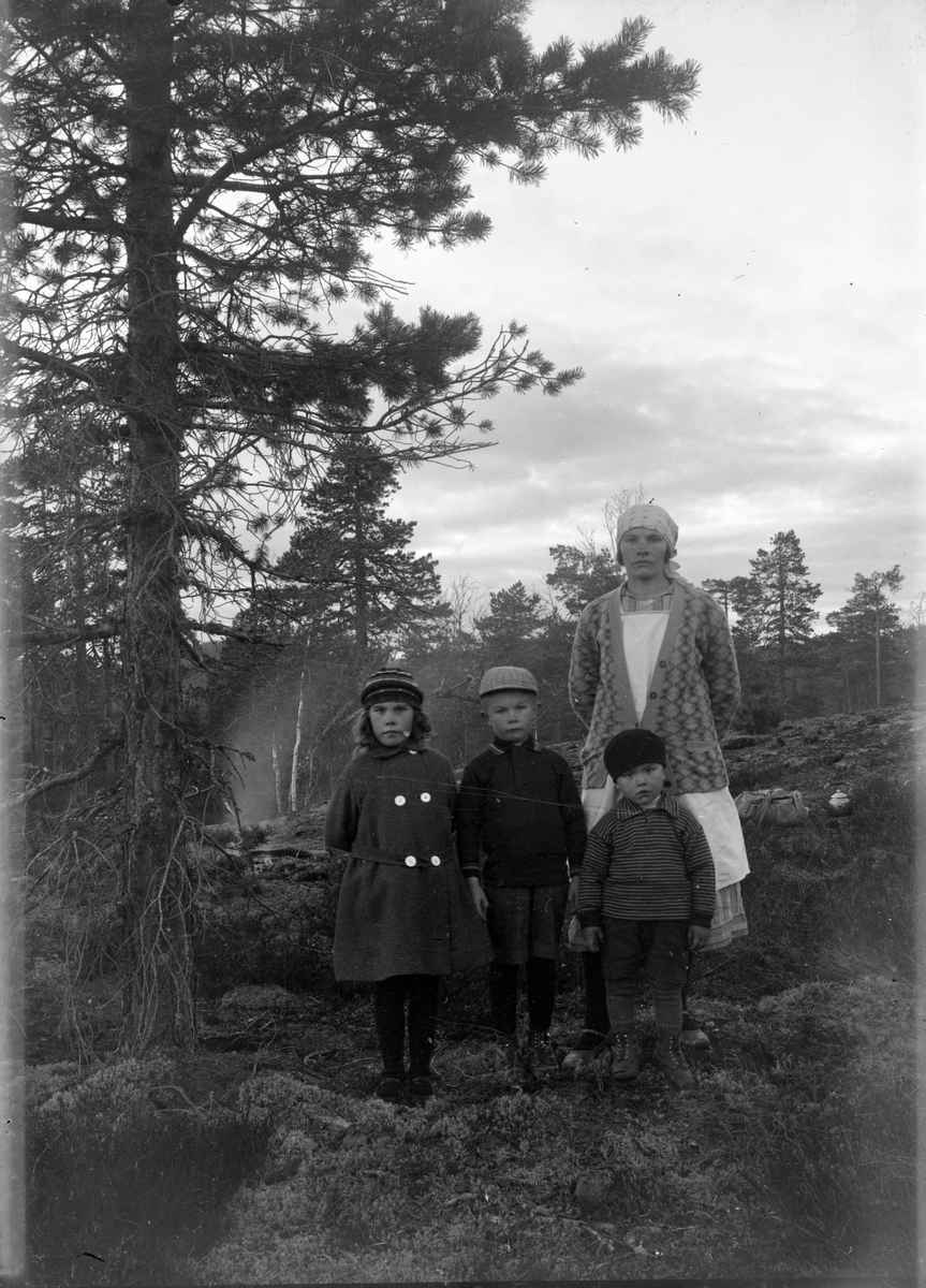 Gruppeportrett, kvinne med tre barn i skogen. Aasta Romsdalen (Klausen) med barn. Gift med Ole Romsdalen 

Fotosamling etter fotograf og skogsarbeider Ole Romsdalen (f. 23.02.1893).