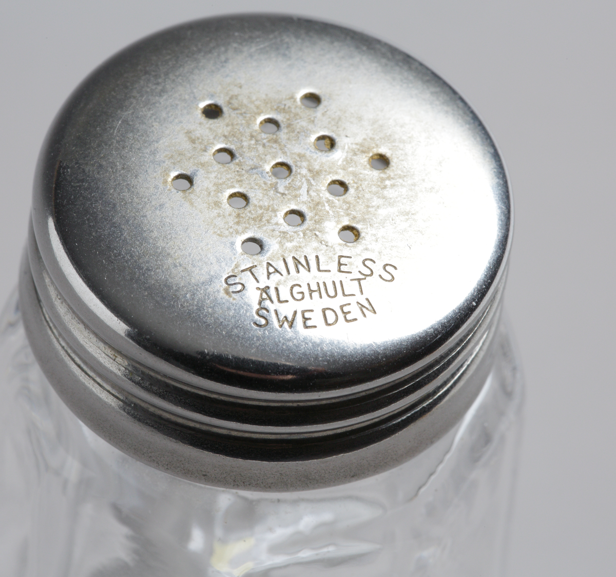 Maskinblåst (halvmaskinell) med stående optik och strölock i rostfritt stål. På strölocket texten: STAINLESS ÄLGHULT SWEDEN".