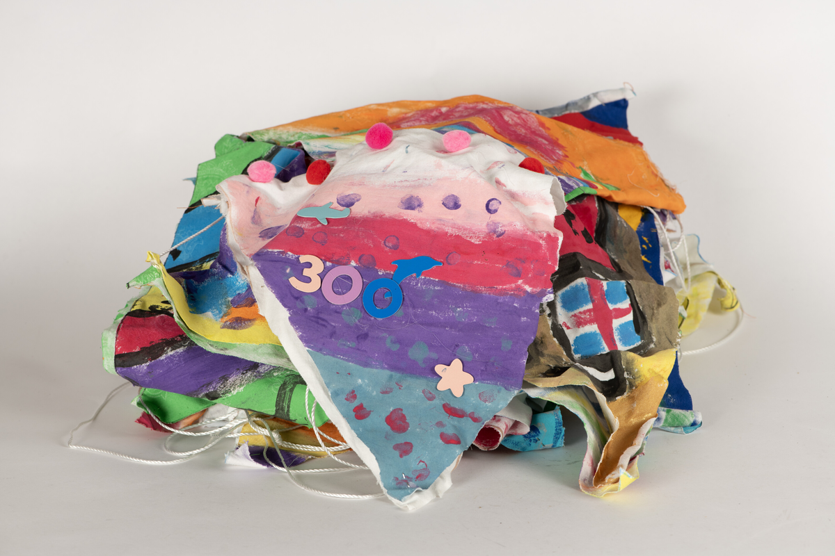 Doble stoff-trekanter dekorert av skoleelever i Arendal, festet til en lang snor. 32 vimpler. Alle har ulik dekor/motiv.