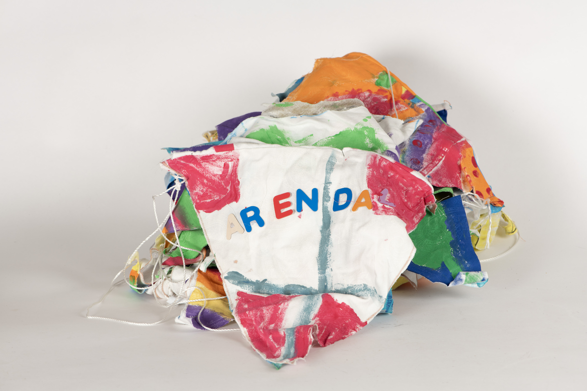 Doble stoff-trekanter dekorert av skoleelever i Arendal, festet til en lang snor. 32 vimpler. Alle har ulik dekor/motiv.