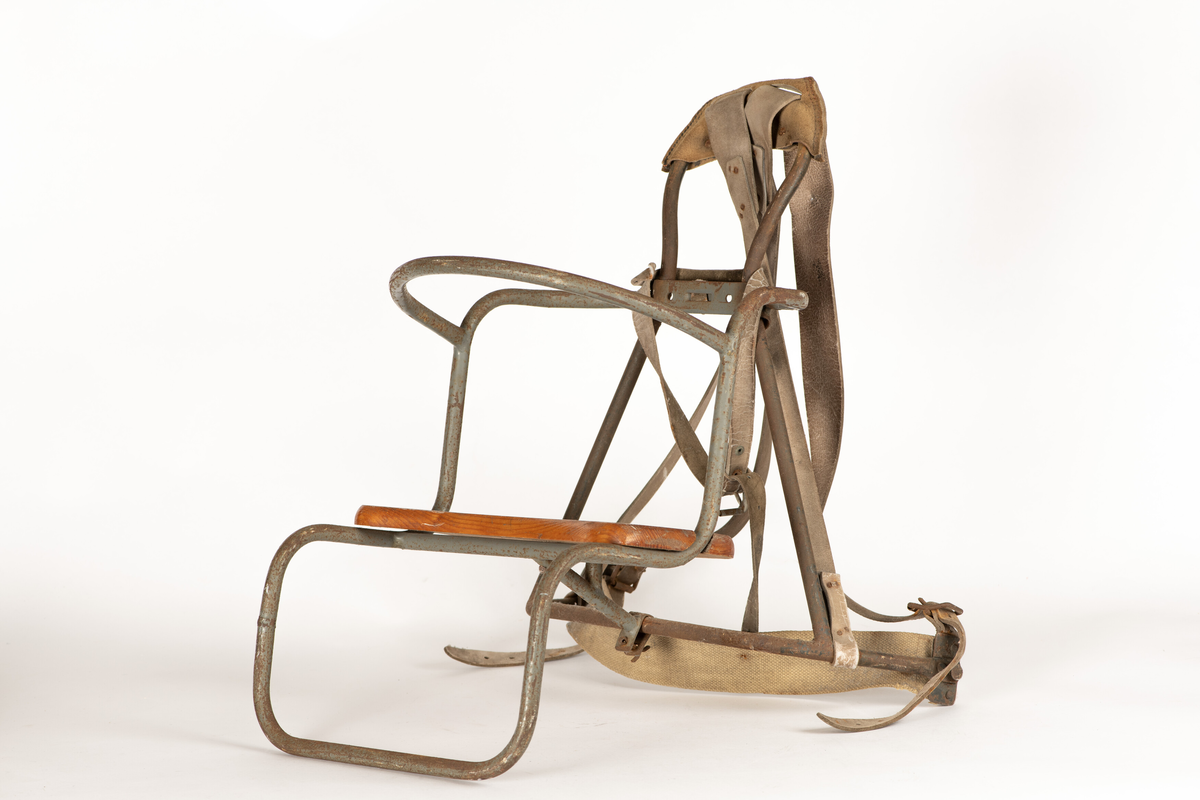 Bæremeis for å bære barn på ryggen. Bergans meispatent med stativ for rygg og sete laget av jernrør. Ryggreimer i lær, reim for korsrygg i grov lerret. Sete i tre.