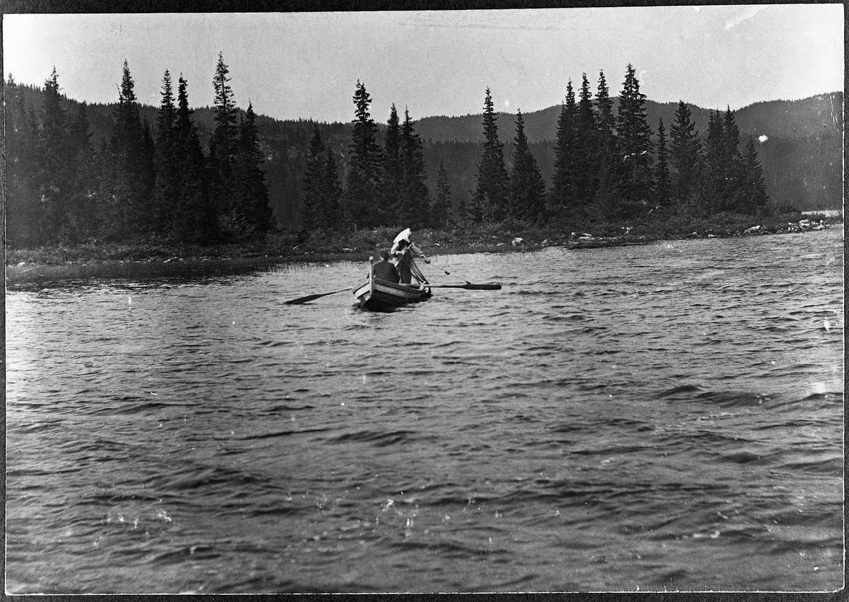 Fiskegarn tas opp i et tjern på Totenåse året 1915. Johanne Marie Nygård håndterer garna, jens Ramstad ror.