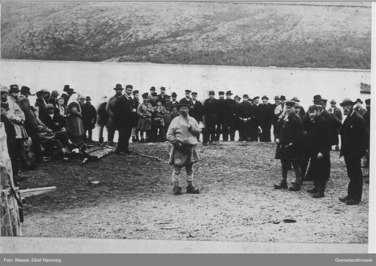 Tekst på baksiden av bildet: "Sosialistisk agitasjonsmøte under valget i 1897. Bildet er tatt i fjæra nedenfor kommunehuset på Kirkenes. E. W."

