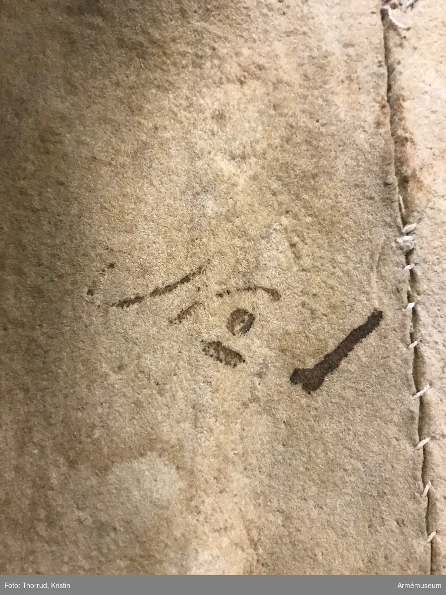 Kyller av gul älghud med smala blå linneband som kantning på insidan samt som passpoal vid övre kant av ärmuppslagen.
Helt framstycke med utsvängt kort skört med uppvik framtill, samt bakstycke med mitt-bak-söm och två sidstycken. Sidsöm under ärmen. Formad tvåsömsärm med ärmuppslag. Ärmuppslagen har sprund som knäpps med 3 koniska älghudsknappar i varje sida, även om det är utskuret 6 knapphål i höger ärm och 5 i den vänstra. De knapphål som inte används är ihopsydda. Liten axelkarm, samt axelklaffar på båda sidor som är fastsydda vid axelsömmen samt knäpps med älghudsknapp vid halsen. Knapp saknas på vänster axel.
Låg ståndkrage som har varit kantad på insidan med blått band. Detta saknas i dag.
Plagget knäpps kant i kant med 12 stycken hyskor och hakar mitt fram. Alla sömmar är sydda med oblekt lintråd.
Märkt inuti ryggen "No 1".
Kyllret skiljer sig något från samtida kyller av samma modell genom att de blå banden är smalare.