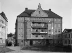 Hospitalstorget 2 i Linköping, uppförd av byggmästaren Anders Ohlsson med 1914 som annonserat slutdatum. För husets ritningar stod den för Linköping så betydelsefulle Axel Brunskog. Bilden är odaterad men bär tydlig prägel av att ha tillkommit kort efter färdigställandet. Tomten för det imposanta huset hyste tidigare stadens hospital inklusive Hospitalskyrkan, som revs redan 1897. I samband med saneringen av det gamla sjukhusområdet lades upplysningsvis Hospitalsgränd ut vid sidan av Ohlssons hus och förbinder sedan dess Hospitalstorget med Drottninggatan. En uppgift direkt knuten till huset är att fasaden kom att förenklas efter en eldsvåda 1960 med en nödtvungen renovering som följd.

Märk väl att glasnegativ i realitet är itusprucket, och att digital bearbetning utförts för den presenterade bilden. Detta sagt som förklaring för de skevheter som kan uppfattas i fotografiet.