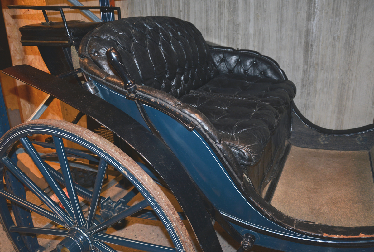 Fra protokollen: Trille, for en hest. Plass til 4 personer + kusk bak. Skinntrekk sete. Vogna er utstyrt med brems og har jerngjorder på hjula. Blålakkert med kvite render. Phaeton-trille.